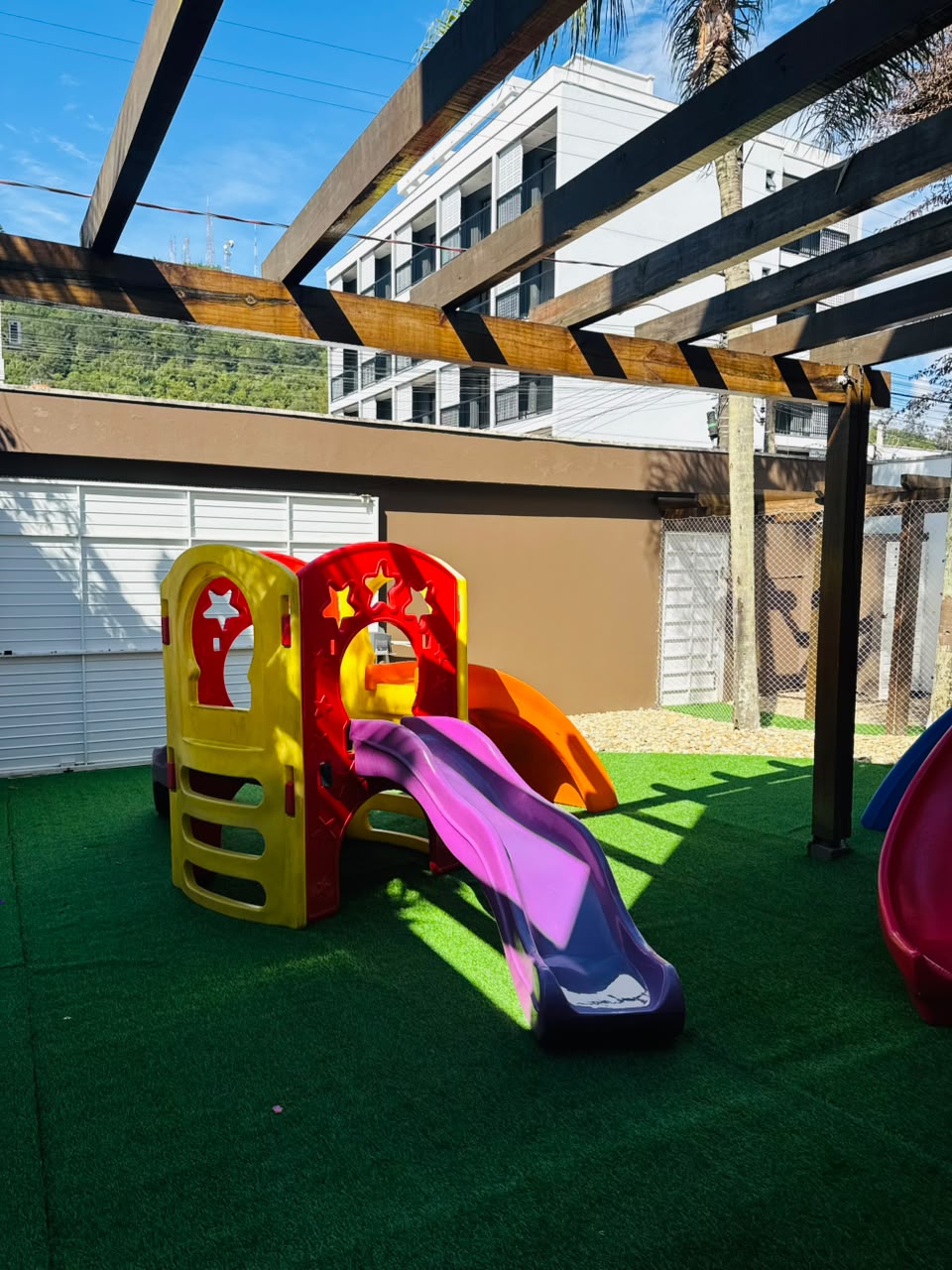 Playground coberto com escorregador e grama sintética
